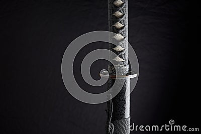 Horizontal photo of sheathed katana with details of the handle and sheath, traditional Japanese sword isolated on black background Stock Photo