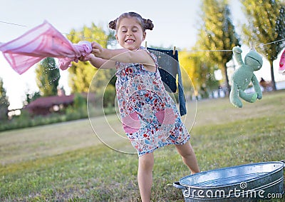 Horizontal photo of a six year old girl who twists the laundry Stock Photo