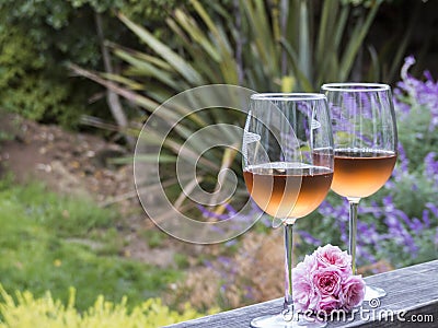 A horizontal photo of two glasses of rosÃ© sitting on an outdoor railing Stock Photo