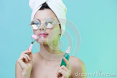 Horizontal photo, a woman with gorgeous skin on a blue background in a towel on her head and body and luxurious glasses Stock Photo