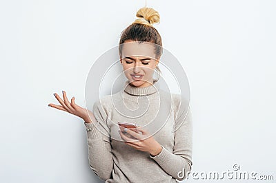 Horizontal portrait of displeased woman has indignant expression while holding smartphone, frowns eyebrows, can`t understand Stock Photo