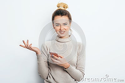Horizontal portrait of displeased woman has indignant expression while holding smartphone, frowns eyebrows, can`t understand Stock Photo