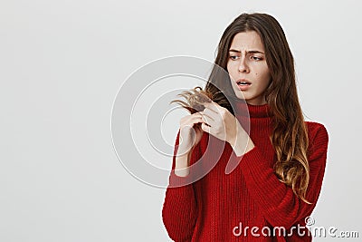 Horizontal portrait of young upset stunned woman in red sweater looking with sad expression of face at her dark long Stock Photo