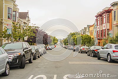 Horizontal shot of a beautiful street with trees, parked cars and classic San Francisco houses on both sides, California - United Stock Photo