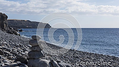 Solitary pebble beach with one rock cairn in a sunny morning, at Playa de San Juan, Tenerife, Canary Islands, Spain Stock Photo