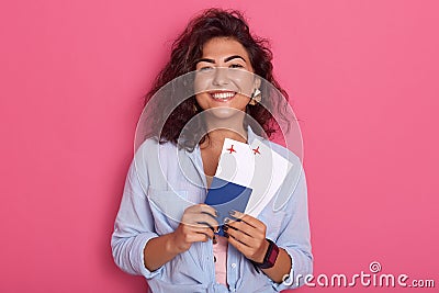 Horizontal shot of charming smiling female with dark hair, looking directly at camera, wearing blue shirt, expressing happyness, Stock Photo