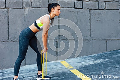 Horizontal shot of the fit woman exercising with resistance band on a sunny day outdoor. Athelte female posing with elastic band Stock Photo