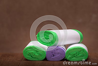 Four roll green eco garbage bag end view with copy space isolated on brown wooden background. Stock Photo