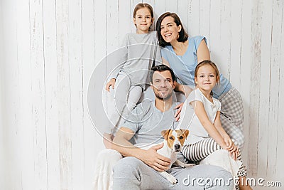 Horizontal shot of friendly family pose together against white b Stock Photo