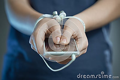 Hands tied with earphone wire. In the hands of the phone. The concept of dependence on gadgets Stock Photo