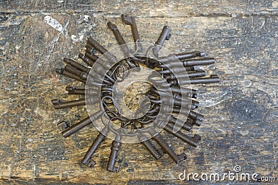 Horizontal shot of many old keys in a single chain placed on a scratched wooden surface Stock Photo
