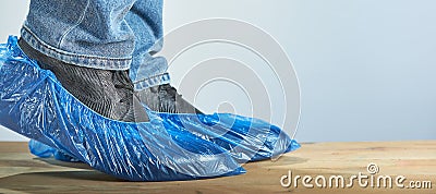 Man with blue shoe covers worn over classic shoes on gray background, closeup. Fight against infection Stock Photo