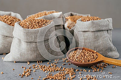 Horizontal shot of roasted buckwheat in sacks and spoon. Gluten free grains. Harvested uncooked cereals. Natural vegan food Stock Photo