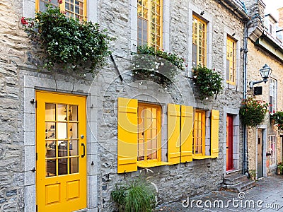 Horizontal side view of 17th Century stone house with bright yellow shutters in the old town Stock Photo