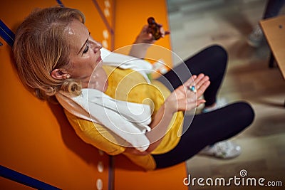 Horizontal top shot of senior woman in gym locker room holdig pills, taking medication and vitamins after workout Stock Photo