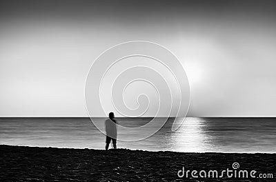 Horizontal vivid black and white lonely man meeting ocean sunset Stock Photo