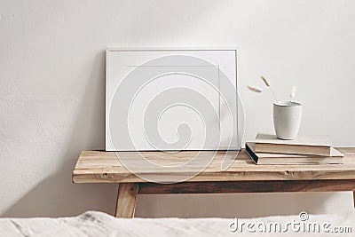 Horizontal white frame mockup on vintage wooden bench, table. Ceramic mug with dry Lagurus ovatus grass and books. White Stock Photo