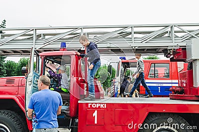 HORKI, BELARUS - JULY 25, 2018: Children of different ages play on the red cars of the rescue service 112 on a holiday in the park Editorial Stock Photo