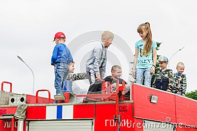 HORKI, BELARUS - JULY 25, 2018: Children of different ages play on the red cars of the rescue service 112 on a holiday in the park Editorial Stock Photo