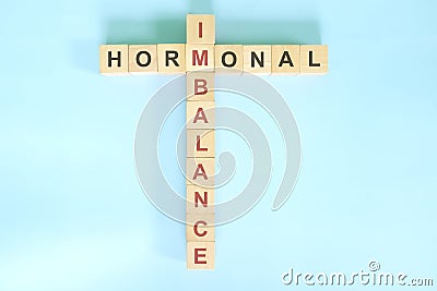 Hormonal imbalance concept. Wooden blocks crossword puzzle flat lay in blue background. Stock Photo