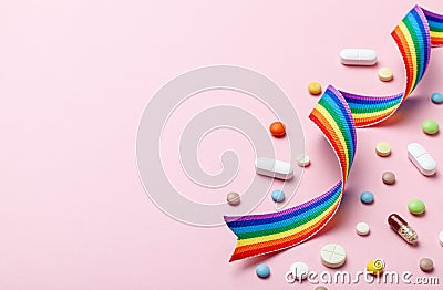 Hormone pills after sex change. Transgender transition. Transvestite. Pride LGBT rainbow ribbon and pills on pink Stock Photo