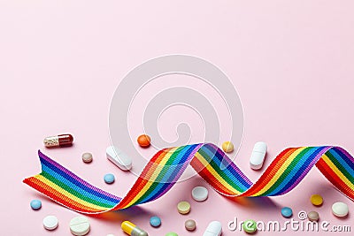 Hormone pills after sex change. Transgender transition. Transvestite. Pride LGBT rainbow ribbon and pills on pink Stock Photo