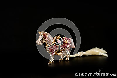 Horse figurine souvenir keychain in gold color ornate with bright pebbles shot on a dark background Stock Photo