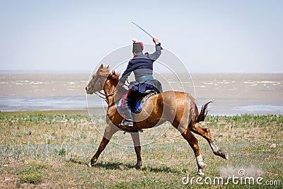 Horseman in blue military clothes riding along the seashore with a sabre in his hand Editorial Stock Photo