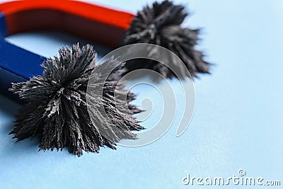 Horseshoe magnet with iron filings on blue background, closeup Stock Photo