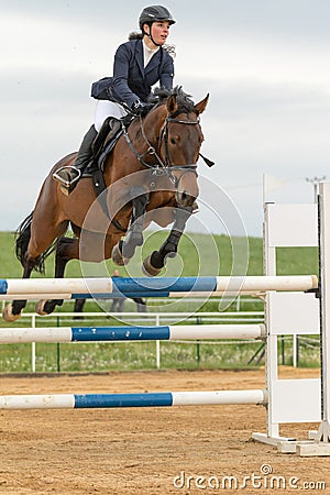 Horsewoman in high jump over a obstacle. Vertically. Editorial Stock Photo