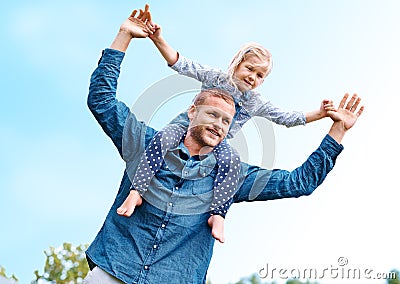 Horsing around with Dad. a happy dad carrying his young daughter on his shoulders. Stock Photo