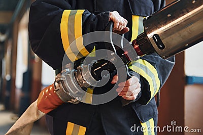 Hose in hands. Female firefighter in protective uniform standing near truck Stock Photo