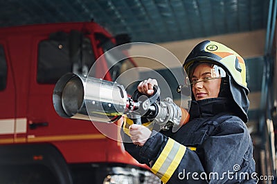 Hose in hands. Female firefighter in protective uniform standing near truck Stock Photo