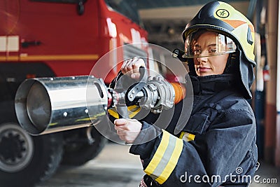 Hose in hands. Female firefighter in protective uniform standing near truck Stock Photo