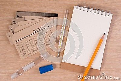 Hospital agenda on doctor table. Calendar, thermometer and pencil on wooden table. Stock Photo