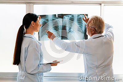 Two doctors examine radiograph for medical xray diagnosis in sterile room. Stock Photo