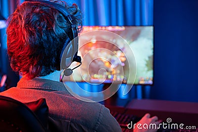 Young gaming streamer playing fighting Moba, wearing headphone and mic. Gusher. Stock Photo
