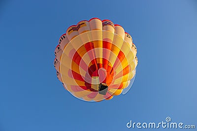 Hot air balloon in clear sky, bottom view. Colorful balloon on blue background. Bright geometric design. Editorial Stock Photo