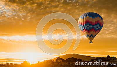 Hot air balloon flying at yellow sunrise Stock Photo