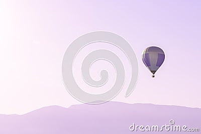 Hot air balloon in the pink sky above soft sunrise mountains silhouettes Stock Photo