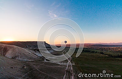 Hot air balloon shadow on the ground during sunrise flying over the valley and mountains Stock Photo