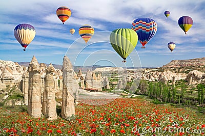 Hot air balloons flying over a field of poppies and rock landscape in Love valley at Cappadocia Stock Photo