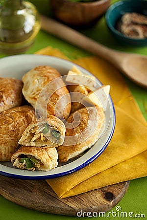 Hot appetizer for family dinner.baked puff pastry pies stuffed with chicken, cheese,pepper on wooden board and green background Stock Photo