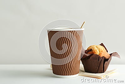 Hot aromatic coffee in paper cup and tasty muffin Stock Photo