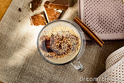 Hot cappuccino with chocolate chips on top of the foam, a cinnamon stick, Golden sugar beads and a sweet waffle next to it Stock Photo