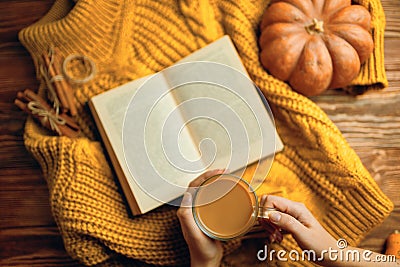 Hot cocoa, ripe pumpkin, warm sweater and open book on wooden background. Stock Photo