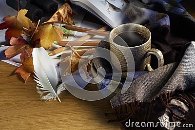 Hot coffee, Autumn leaves, crayons, feather, and a drawing on wood background Stock Photo