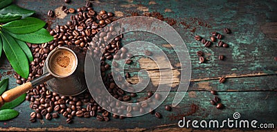 Hot coffee in a coffeepot or turk on a wooden background with coffee leaves and beans, horizontal with copy space Stock Photo