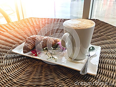 Hot coffee with croissants decorate with flower on rattan table Stock Photo