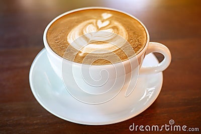 Hot coffee latte cup on wood table background with warm morning Stock Photo